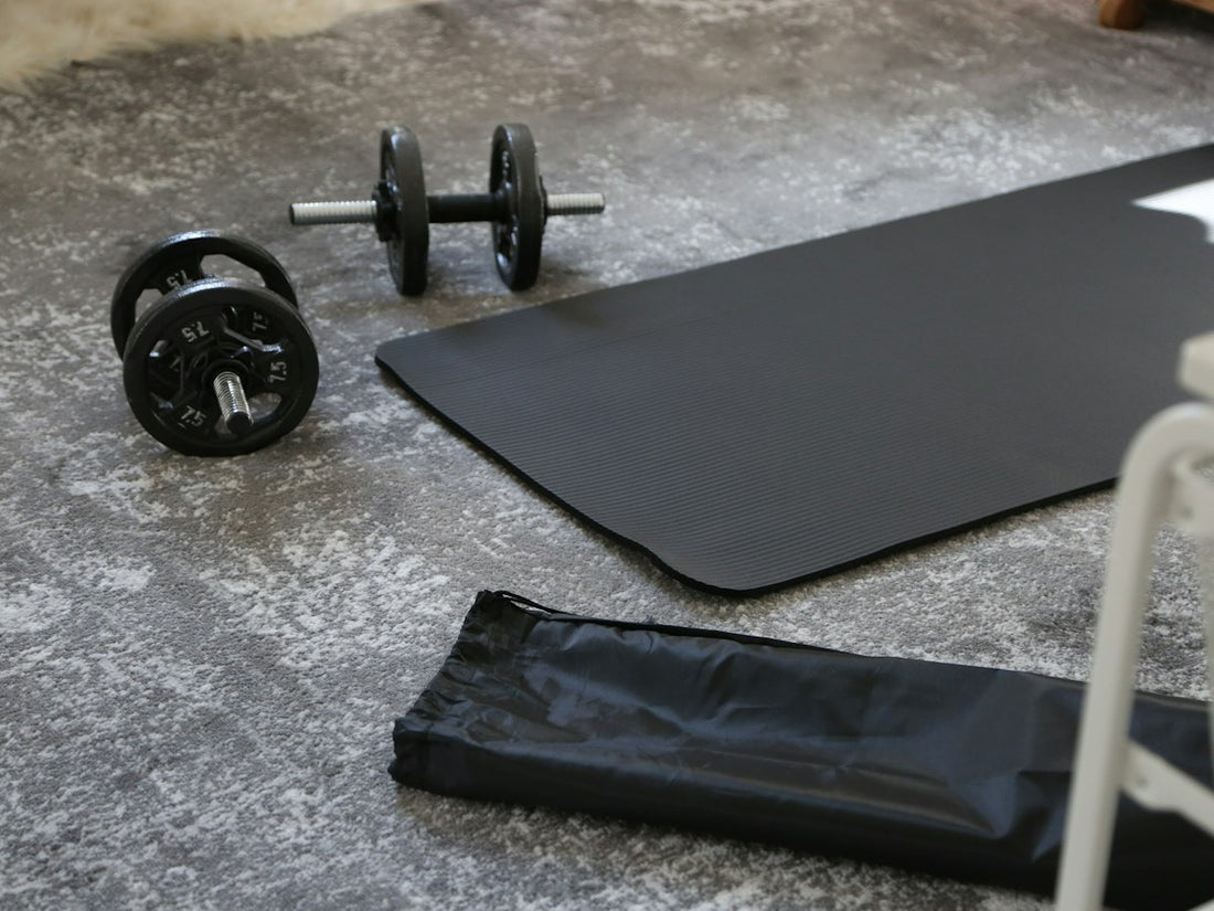 Zwei Kurzhanteln auf einer schwarzen Trainingsmatte, bereit für das Home-Gym-Workout